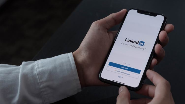 Man holding a phone with LinkedIn on the screen